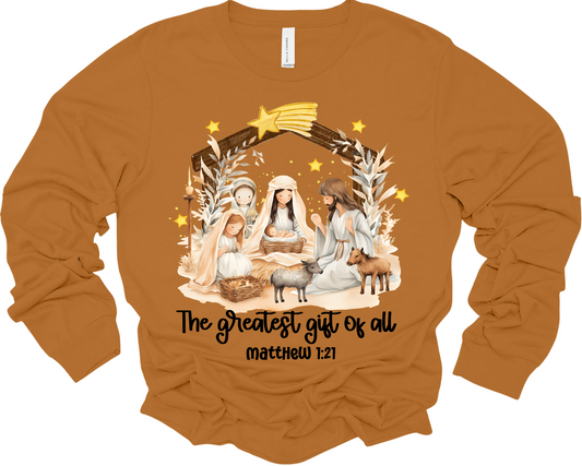 A brown long-sleeved sweatshirt with a graphic of the nativity scene featuring Mary, Joseph, and baby Jesus, and text that reads 'The Greatest Gift of All - Matthew 1:21'.