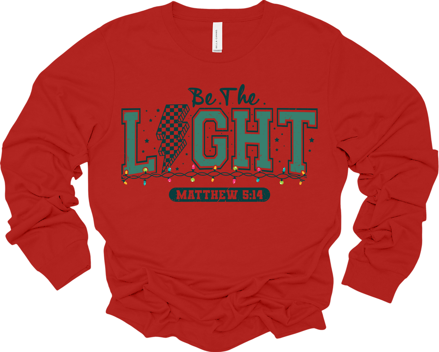 A red long-sleeved t-shirt with a graphic that says 'BE THE LIGHT' and references Matthew 8:14.