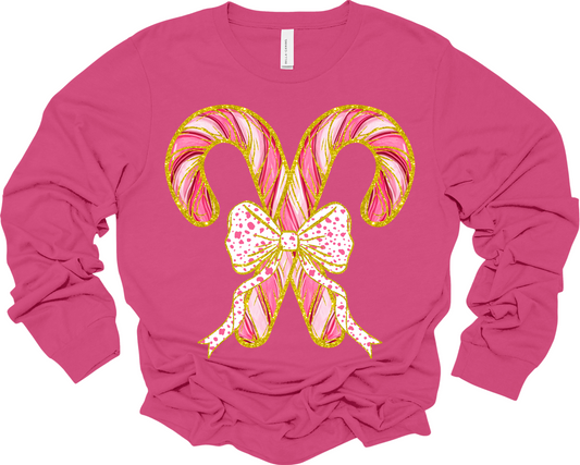 Long sleeve pink t-shirt with two criss crossed candy canes outline in faux gold glitter with a polka dot bow image.